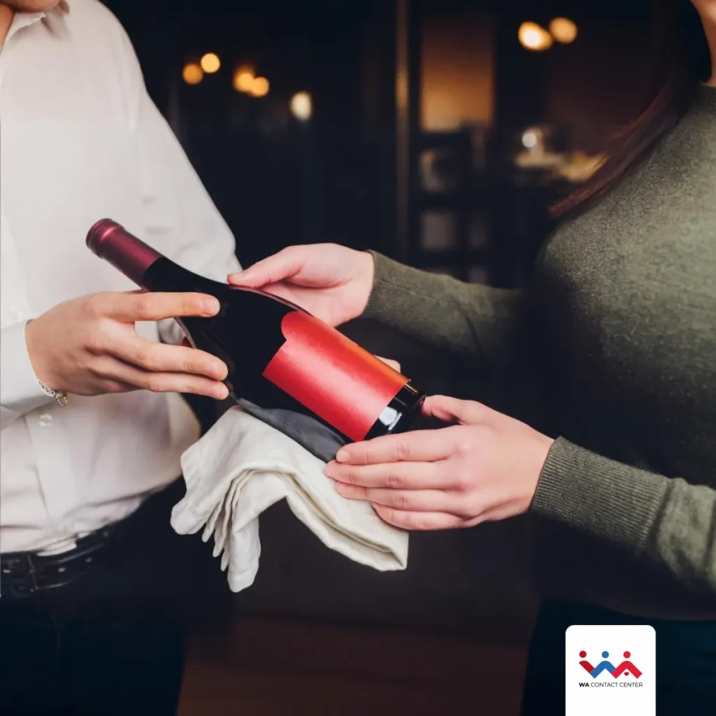 Sommelier mostrando uma garrafa de vinho a uma cliente.